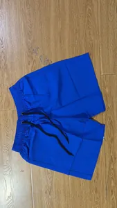 Bright blue men's casual summer shorts with black drawstring on wooden floor background