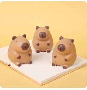 Three cute brown capybara squishy toys on a notebook for stress relief