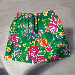 Vibrant green men's beach shorts with traditional floral and phoenix pattern