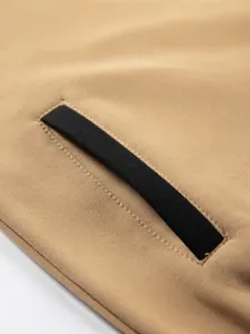 Close-up detail of a khaki fleece hoodie featuring a contrast black pocket welt design