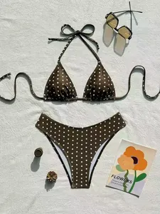 Elegante bikini allacciato al collo a pois marroni su tessuto bianco con occhiali da sole