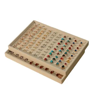 Professional beige velvet jewelry display trays stacked with various rings for retail showcase
