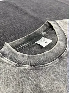 Gedetailleerde close-up van de geribbelde hals en maatlabel van een grijs gewassen t-shirt