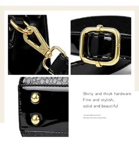 Detail of golden hardware and crocodile embossed patent leather on black handbag.