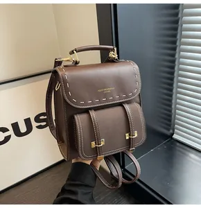 Close-up of a vintage brown leather backpack with detailed white contrast stitching.