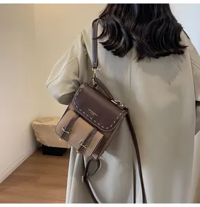 Rear view of model wearing a retro brown color-block backpack with white stitching.