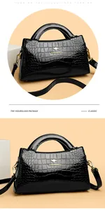 Close-up detail of a black crocodile pattern patent leather handbag with gold kangaroo logo.