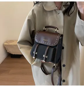 Vintage brown and black leather-style backpack with contrast stitching held by a model.