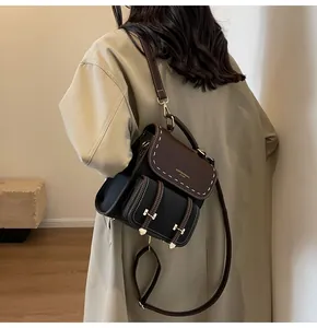 Back view of a stylish vintage black and brown leather backpack worn with a beige coat.