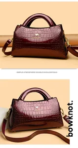 Detailed view of the glossy wine red crocodile embossed texture on a chic handbag