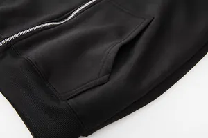 Detail of black zip-up hoodie showing kangaroo pocket and ribbed hem texture