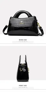 Black patent leather handbag featuring crocodile pattern and elegant gold kangaroo logo
