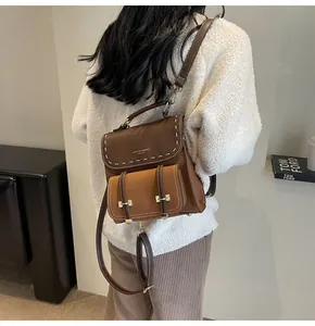 Close-up of a vintage brown leather backpack worn by a model in a minimal setting