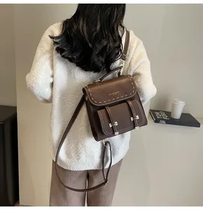 Vintage brown faux leather backpack with white contrast stitching shown on model back