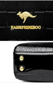 Close-up of gold kangaroo logo and metal studs on black crocodile patent handbag