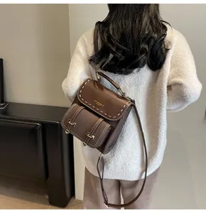 Detailed back view of a stylish brown vintage leather backpack worn by a female model.