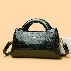 Elegant dark green crocodile embossed patent leather handbag with top handle.