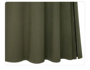 Detail close-up of dark green ribbed knit fabric and side slit hem of a midi skirt.