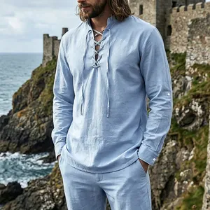 Detail view of men's medieval light blue linen lace-up shirt in a coastal castle setting