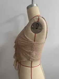 Detailansicht eines beigen Spitzen-Camisoles mit Rüschenbesatz auf einer Schneiderpuppe.