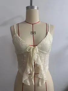 Detaillierte Nahaufnahme eines weißen floralen Spitzen-Tops mit vorderer Schleife