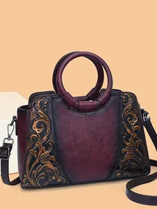 Vintage embossed burgundy leather handbag with intricate floral patterns and ring handles