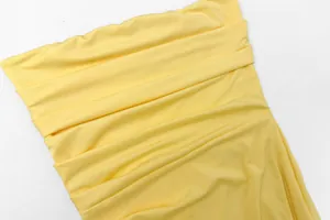 Detailed close-up of the yellow ruched fabric texture on a sexy strapless summer dress
