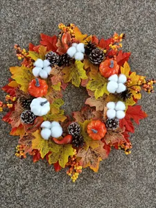 Détail rapproché d'une couronne d'automne avec feuilles d'érable, citrouilles et pins.