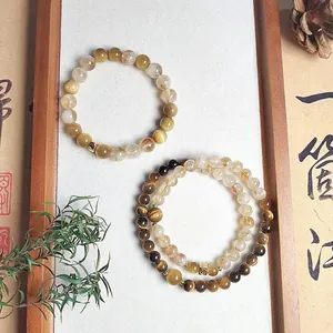 Close-up of natural tiger eye and citrine beaded bracelets in a wooden frame