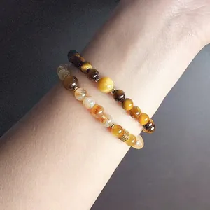 Close-up of natural tiger's eye and citrine beaded bracelet on female wrist