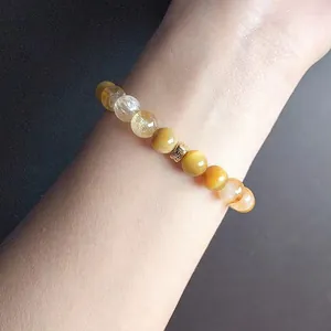 Close-up of a natural yellow tiger eye and citrine beaded bracelet worn on a woman's wrist