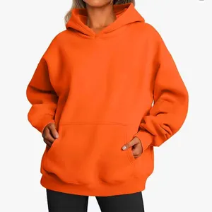 Detail showing the soft texture and kangaroo pocket of this oversized orange hoodie.