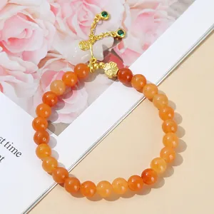 Elegant red aventurine jade beaded bracelet with golden lucky bag and clover charms.