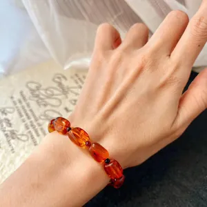 Macro detail of a retro natural amber beeswax beaded bracelet worn on an elegant hand