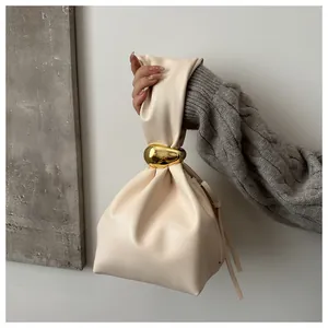 Detail view of a beige retro pleated bucket bag with a stylish gold buckle accent.