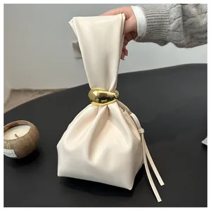 Close-up of cream vintage pleated bucket bag featuring elegant gold metal ring handle
