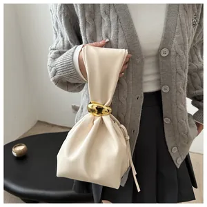 Close-up detail of vintage cream pleated bucket bag with a chic gold metal ring clasp