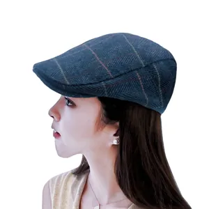 Side profile of a woman wearing a blue herringbone wool newsboy cap, isolated on white.