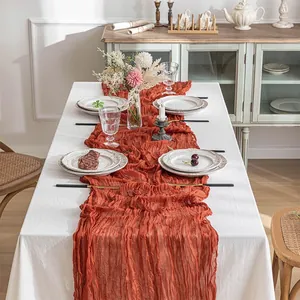 Detailed view of a burnt orange cheesecloth gauze table runner with pleated texture