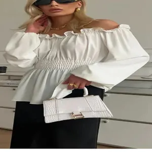 Detailed view of a white off-the-shoulder blouse with ruffled trim and puff sleeves