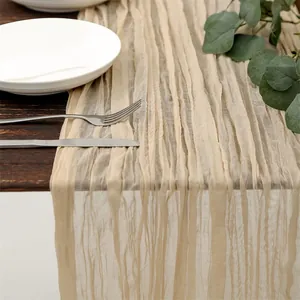 Beige cheesecloth table runner with natural wrinkled texture on dark wood table