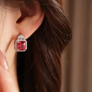 Primo piano di un elegante orecchino in zircone rosso quadrato con incastonatura a aureola