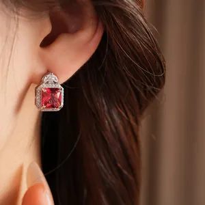 Dettaglio di un orecchino quadrato con zircone rosso e cornice di pietre bianche