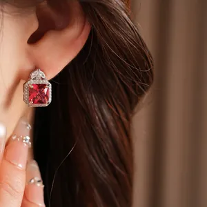 Dettaglio ravvicinato di lussuosi orecchini in zircone rosso quadrato con montatura halo.