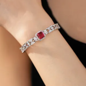 Dettaglio di un bracciale argento con un grande zircone rosso quadrato e pietre bianche