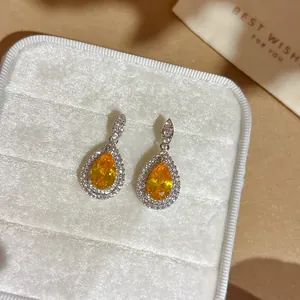 Elegante tropfenförmige Ohrringe mit orangefarbenem Zirkon in einer weißen Samtbox