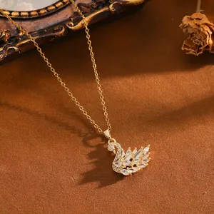 Elegante collana con ciondolo a cigno dorato con zirconi incastonati su sfondo di sabbia