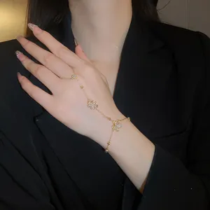 Close-up of gold-plated harness bracelet with cubic zirconia flowers on woman's hand.