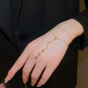 Close-up of a 14k gold plated hand chain with flower and geometric zircon pendants
