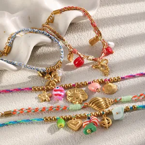 Close-up of colorful woven bracelets with gold charms like shells and hearts